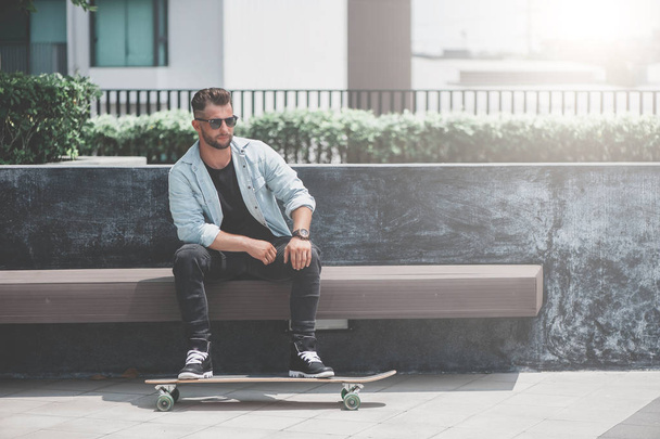 Man sit with skateboard. - Фото, зображення