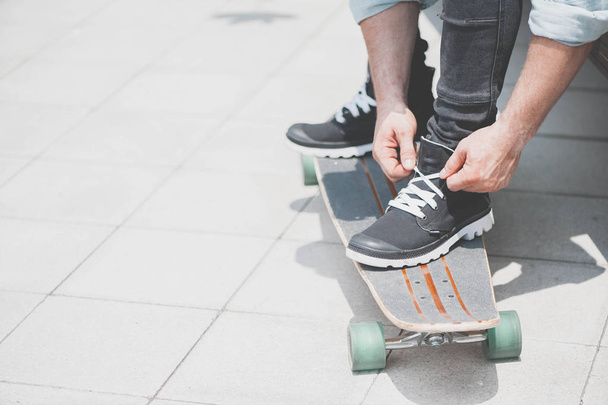 A skateboarder tying shoelaces - Фото, зображення