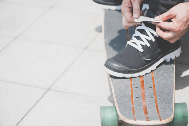 A skateboarder tying shoelaces - 写真・画像