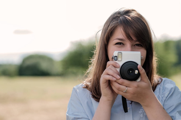 Lovely young long-haired girl with instant camera. - Photo, Image