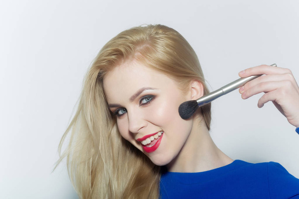 Happy woman applying makeup on face with powder brush - Fotoğraf, Görsel
