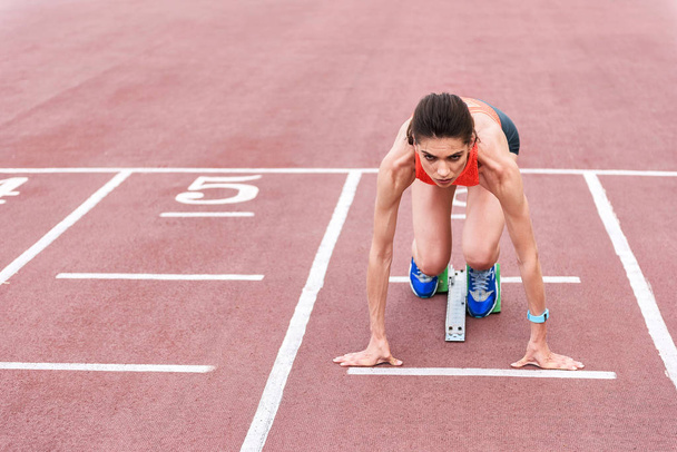 Confident girl posing in blocks to start running - Фото, изображение