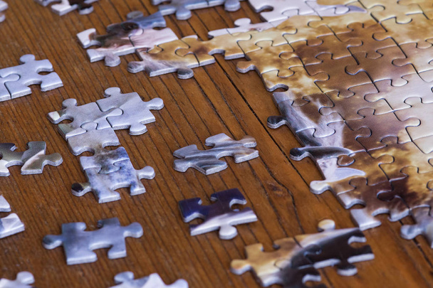 Pezzi sparsi di puzzle sul tavolo di legno. Sforzo di mettere insieme le cose
. - Foto, immagini
