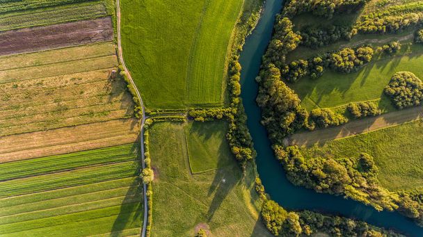 River bend surrounded by fields from birds eye view. - Foto, Imagen