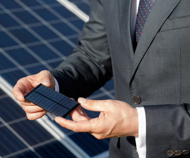 Homme d'affaires tenant l'élément photovoltaïque dans ses mains
. - Photo, image