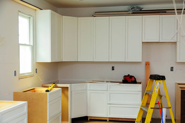 Aangepaste keukenkasten in verschillende stadia van de installatie base voor eiland in centrum installatie van keukenkasten - Foto, afbeelding