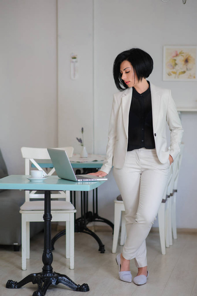 business lady dressed in white suit working on a laptop - Foto, afbeelding