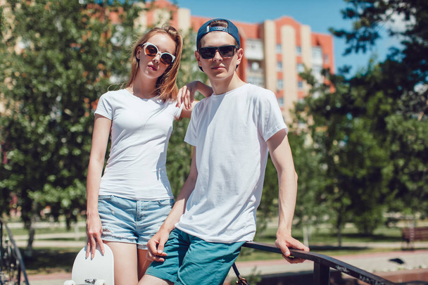Young skater boy and girl with skateboard in white T-shirts on the street. Mock up. - Fotó, kép