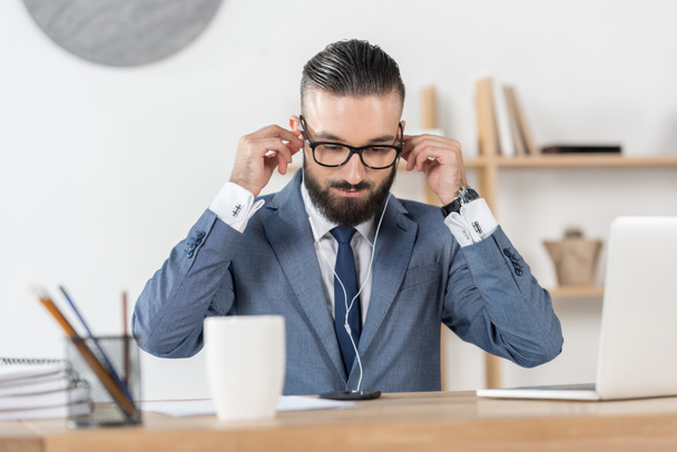 businessman in earphones at workplace - Фото, изображение