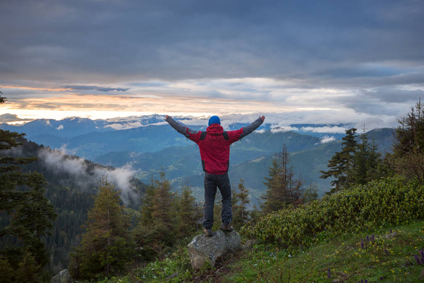 Eenzame reiziger met open armen staat op de klif in de mounta - Foto, afbeelding