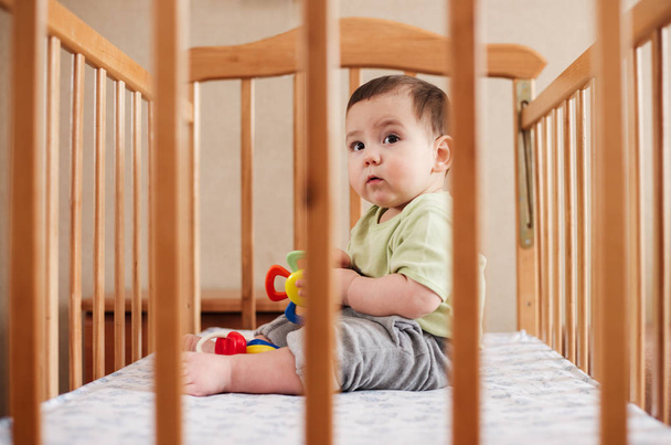 Adorable baby boy sitting in his cot or crib - Fotoğraf, Görsel