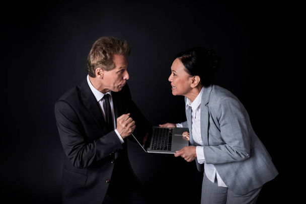 colegas de negocios luchando por el ordenador portátil
   - Foto, Imagen