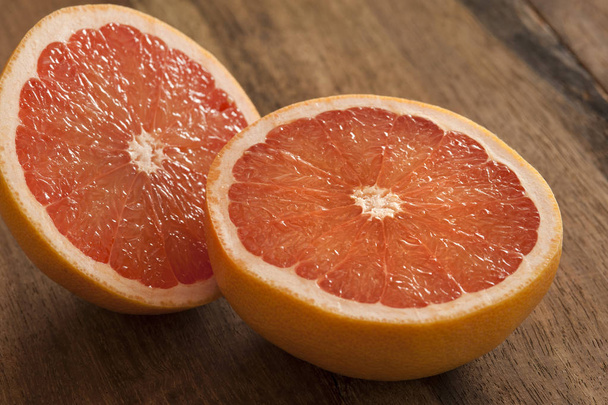 Pink grapefruit cut in half on wooden table - Photo, Image