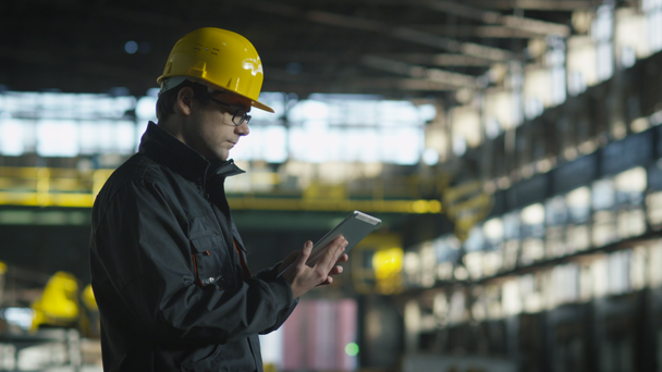 Techniker in harter Mütze bei der Arbeit im industriellen Umfeld. Tablet in den Händen halten. - Filmmaterial, Video