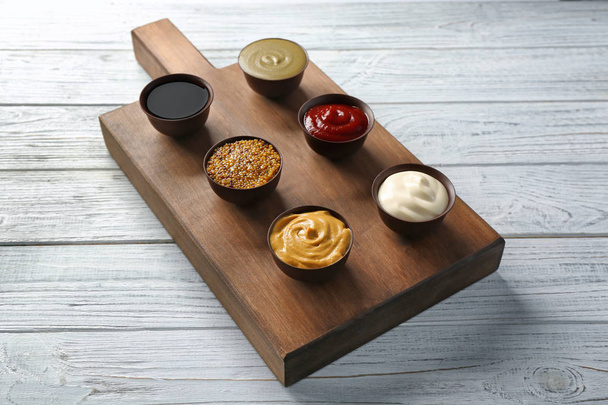 Board with different sauces on wooden background - Φωτογραφία, εικόνα