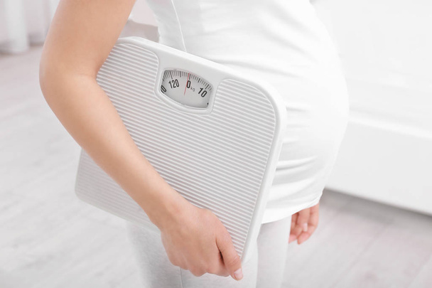 Pregnant woman with scales at home. Pregnancy weight gain concept - Fotoğraf, Görsel