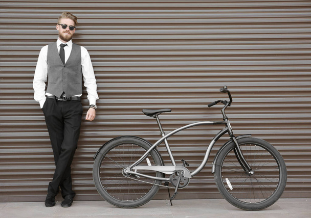 Young man with bicycle on color wall background - Foto, immagini