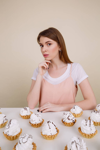 Amazing young lady sitting and posing near cupcakes - Valokuva, kuva