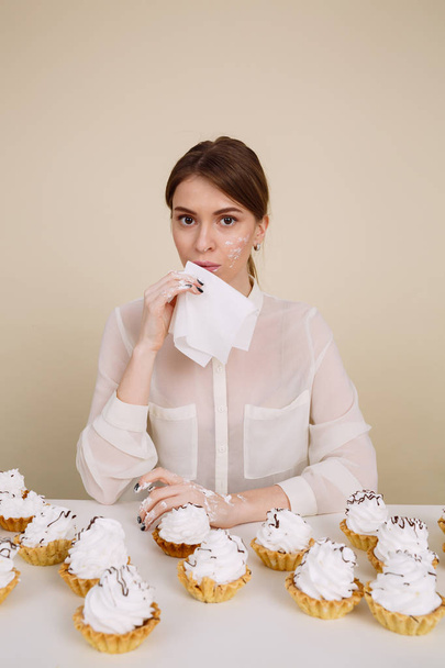 Amazing young lady posing while eating cupcakes holding napkin. - Foto, Imagen