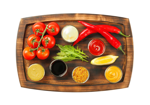 Wooden plate with different sauces and vegetables on white background - Photo, image