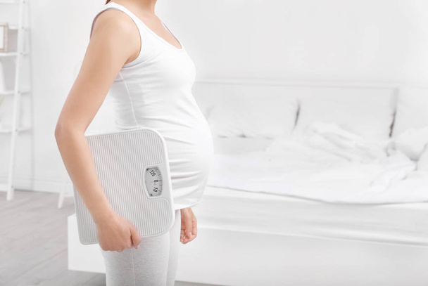 Mujer embarazada con escamas en casa. Concepto de aumento de peso durante el embarazo
 - Foto, Imagen