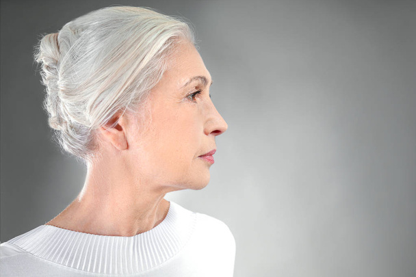 Beautiful elegant elderly woman on gray background - Zdjęcie, obraz