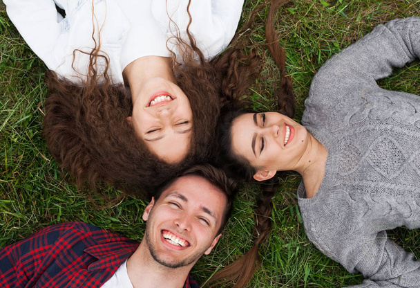 young friends lying on grass - Фото, изображение