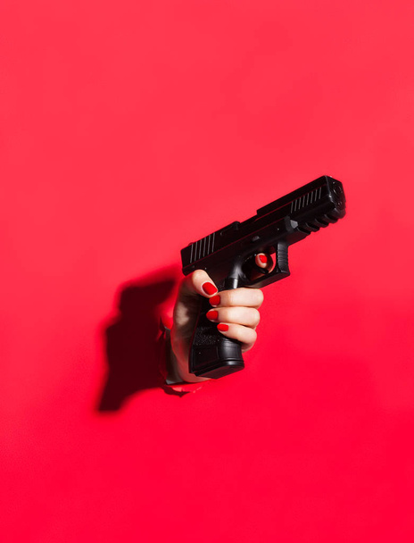 hand with manicure holding gun - Photo, image