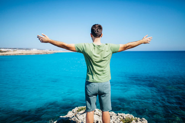 young man with open arms on cliff  - Foto, Bild