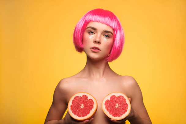 Model in wig posing with grapefruits - Фото, зображення