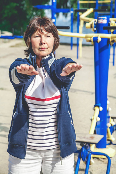 Cute retired woman performs gymnastic exercises on street - Foto, Bild