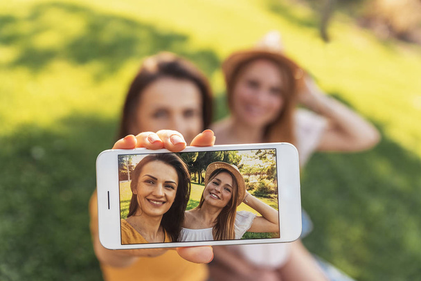 Beautiful women taking a selfie portrait in the park. - Photo, Image