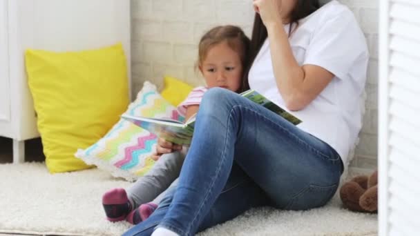 Young mother reading book for her little daughter. - Felvétel, videó