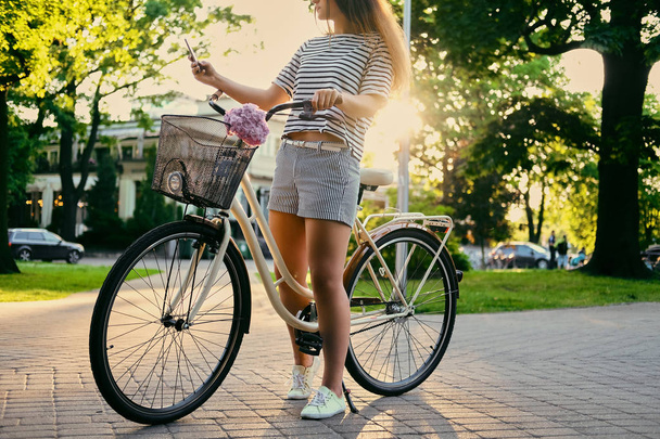 Brunette woman in a park on a bicycle - Fotó, kép