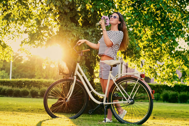 Vrouw houdt boeket in de buurt van de stad fiets - Foto, afbeelding