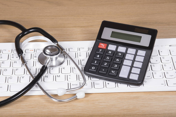 Stethoscope and calculator on a computer keyboard - Photo, Image