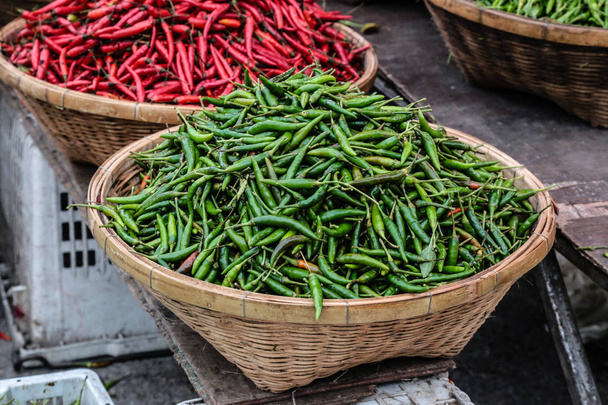 Green and red peppers in wooden baskets for sale in outdoor markets. - Photo, Image