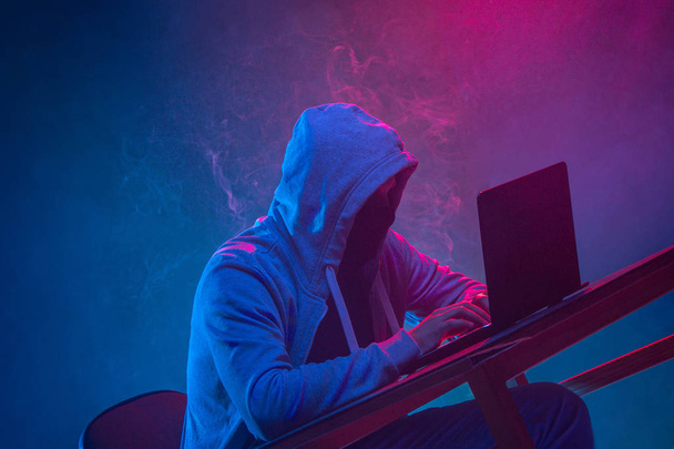 Hooded computer hacker stealing information with laptop - Foto, immagini
