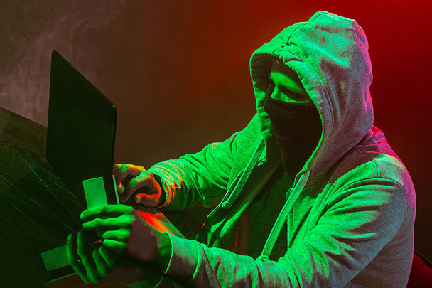 Hooded computer hacker stelen van informatie met laptop - Foto, afbeelding