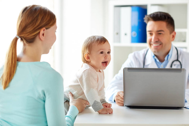 woman with baby and doctor with laptop at clinic - Foto, Bild