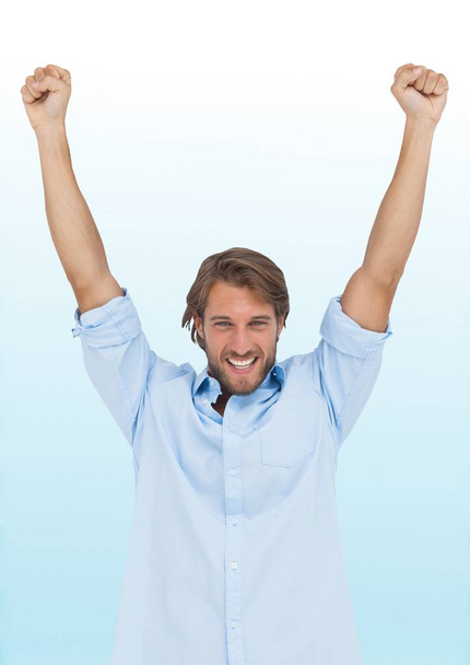 Man celebrating against blurry blue and white background - Foto, immagini