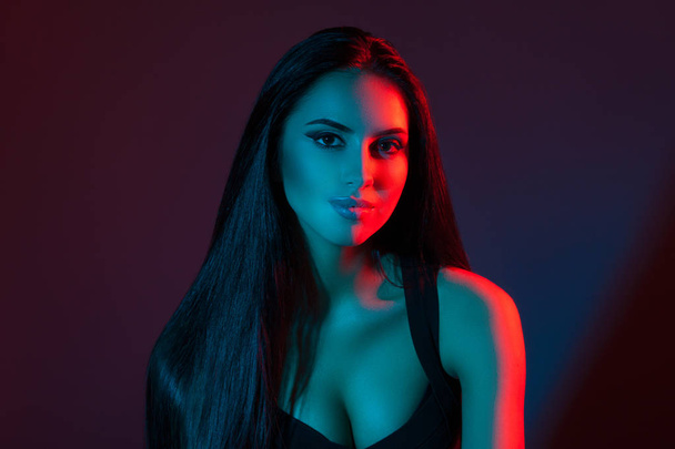 Studio creative portrait of a beautiful model girl. Brunette in red and blue light - Foto, afbeelding