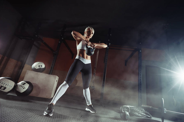Gespierde jonge fitness vrouw tillen een gewicht in de sportschool - Foto, afbeelding