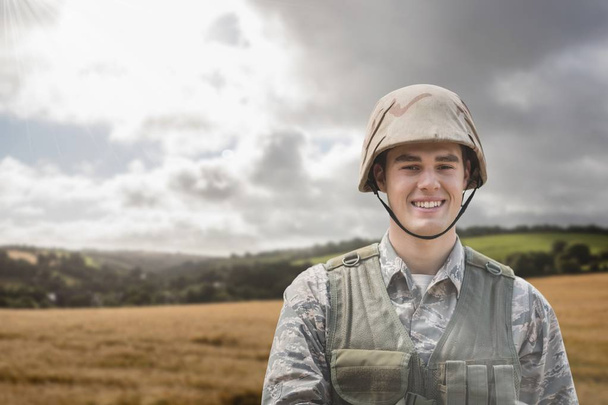 Happy soldier man standing against field background - 写真・画像