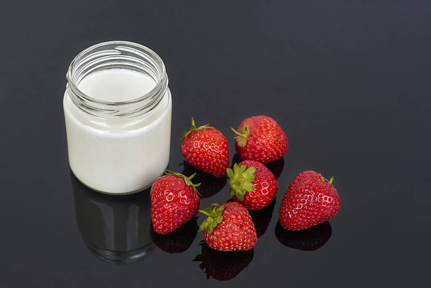 Yogur en frasco de vidrio y fresas sobre fondo negro - horizontal
 - Foto, imagen