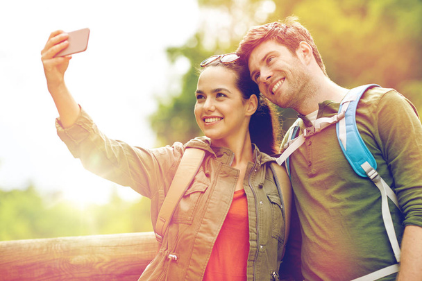 couple with backpacks taking selfie by smartphone - Фото, зображення