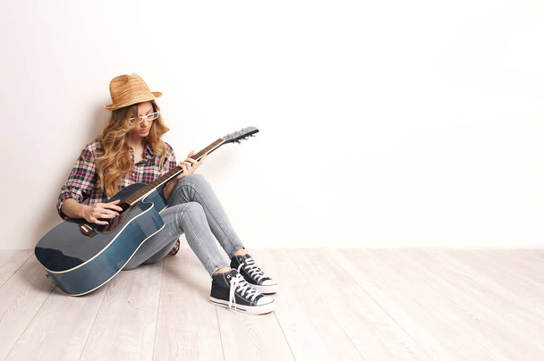 Belle femme assise avec sa guitare assise sur le sol en bois
 - Photo, image