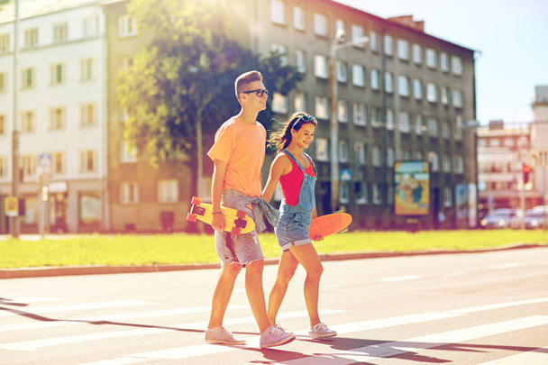 teenage couple with skateboards on city street - Фото, изображение