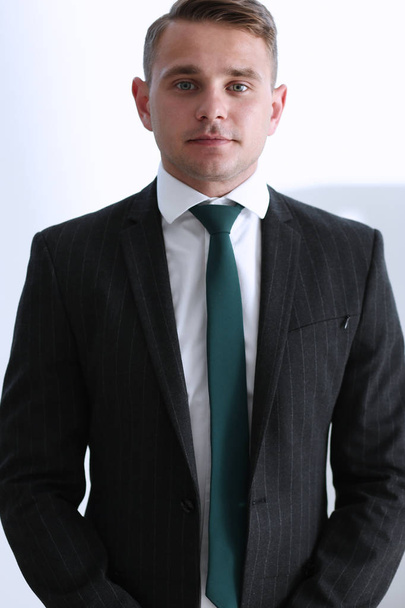 Przystojny człowiek uśmiechający się w garnitur i krawat stoją w biurze - Zdjęcie, obraz