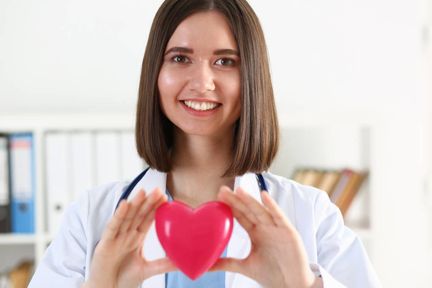 Medizinerin hält rotes Spielzeugherz in den Händen  - Foto, Bild
